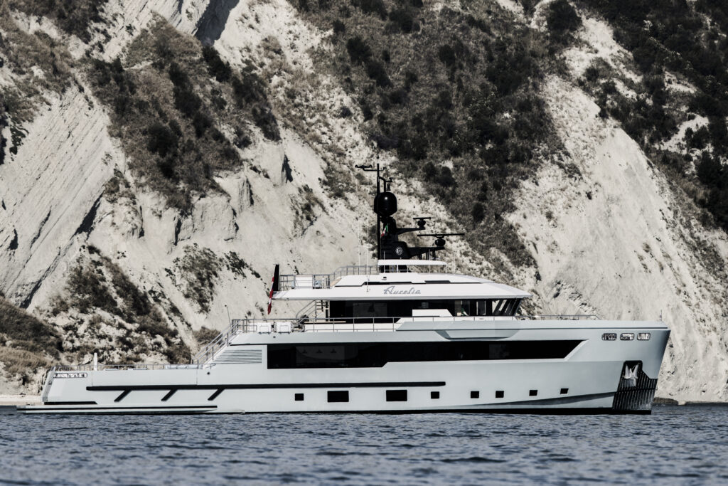 Cantiere Delle Marche Flexplorer 130 pictured from side with dramatic cliffs in background