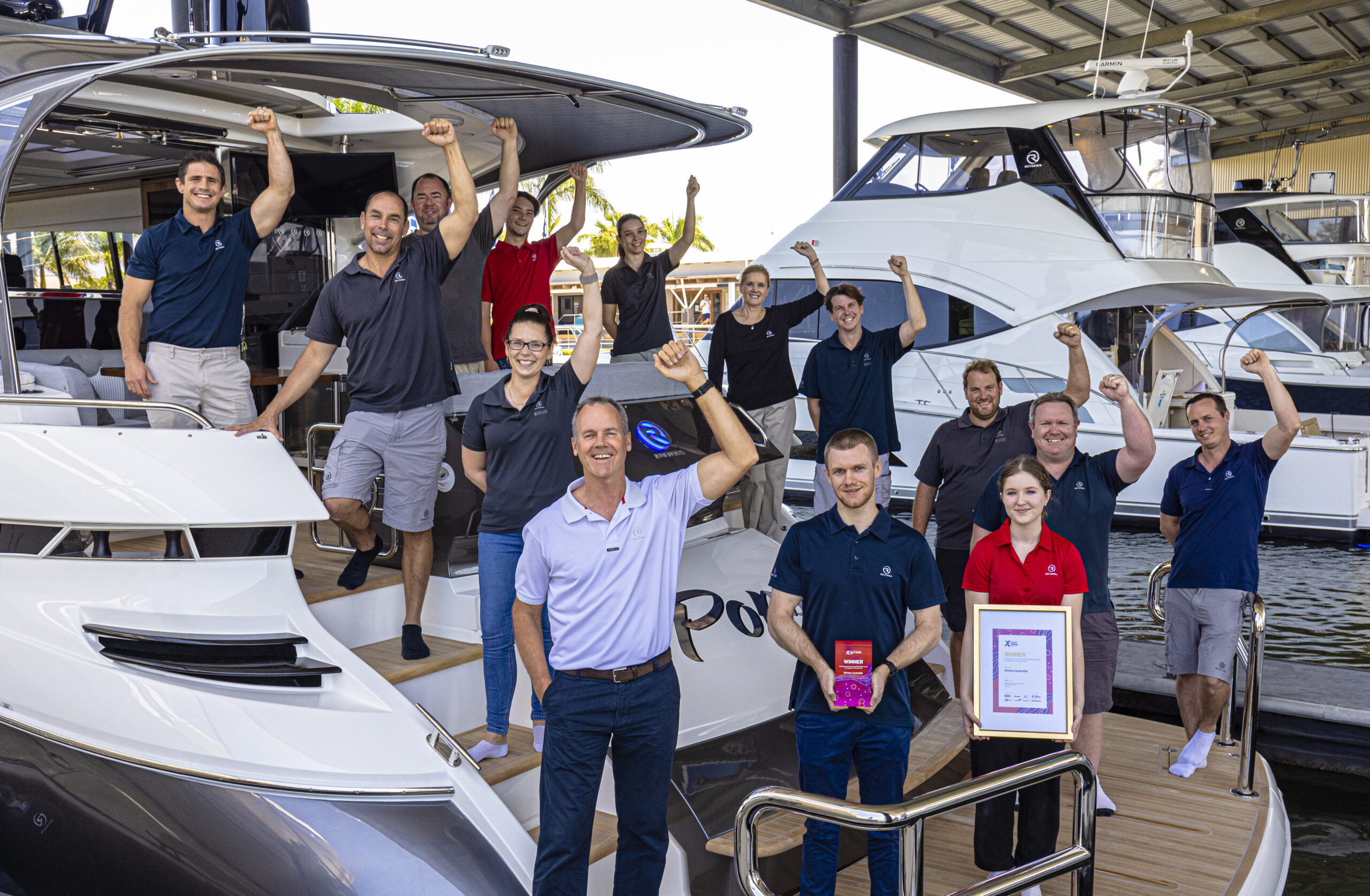 Riviera team celebrating their Export award on the aft of a Riviera vessel