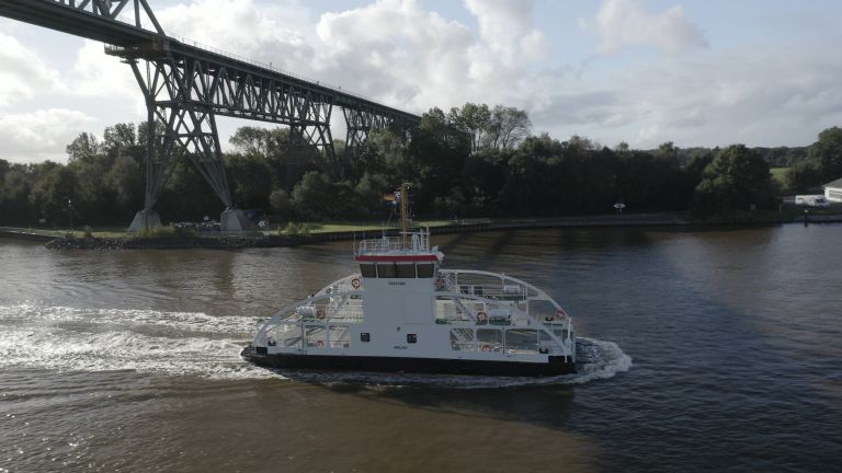 electric passenger ferry cruising under a bridge