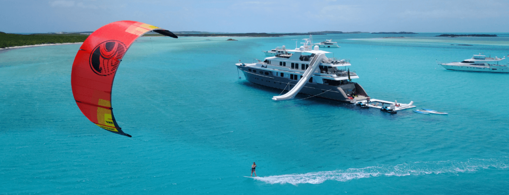 shot of motor yacht on clear blue seas with wind surfer in foreground