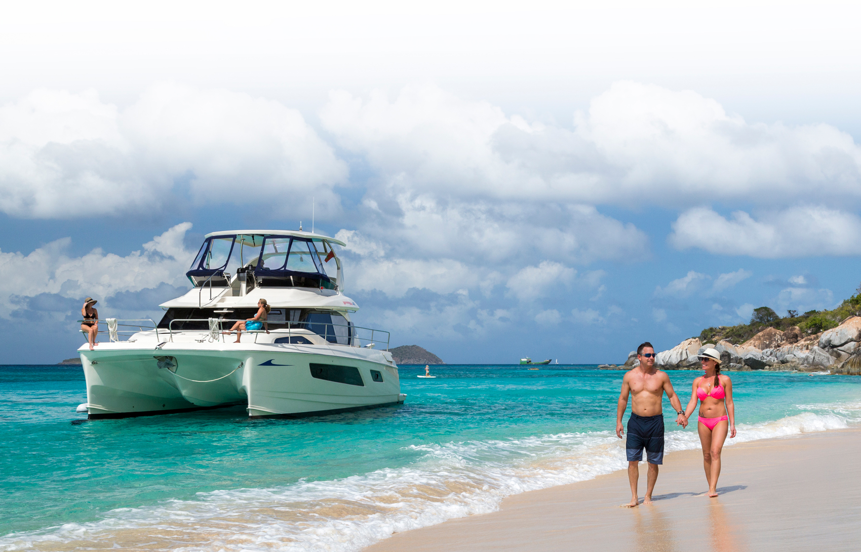 MarineMax vessel near the shore of a beach with couple walking in foreground
