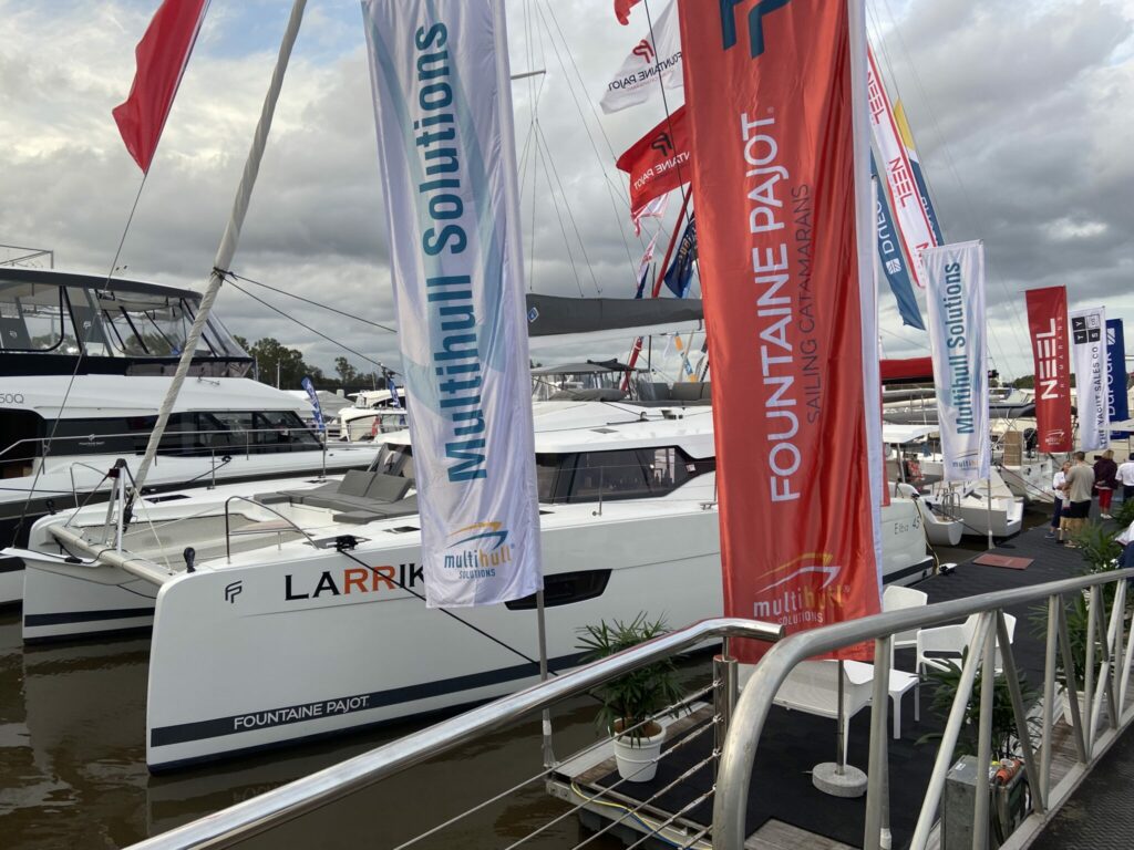Multihulls on dock with flags around.